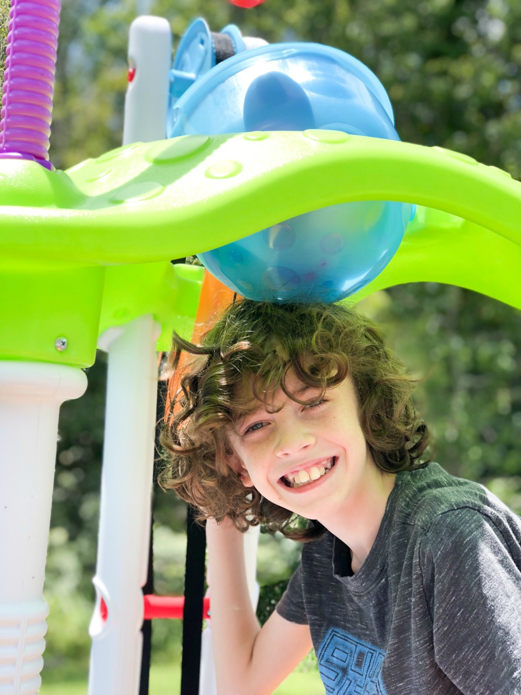 boy smiling while playing with little tykes tower