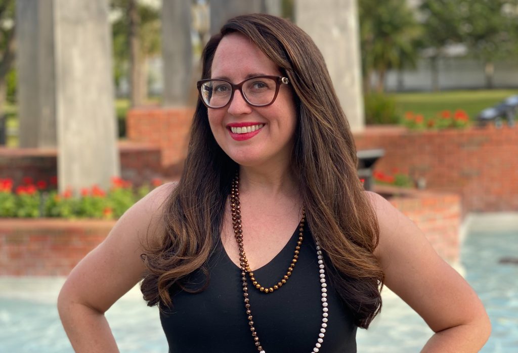 brown haired woman wearing black to standing in front of a fountain