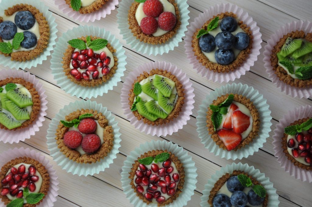 fruit tart desserts in cupcake liners on top of white wooden table