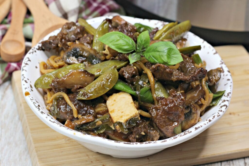 Thai steak dish in white bowl on wooden tray
